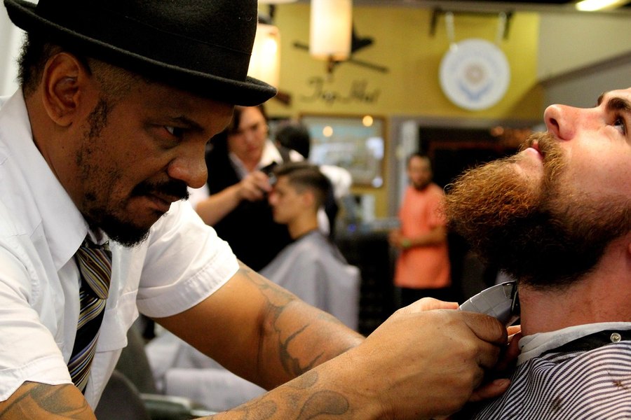 Barbero recortando la barba de un cliente en el sillón (imagen de referencia)
