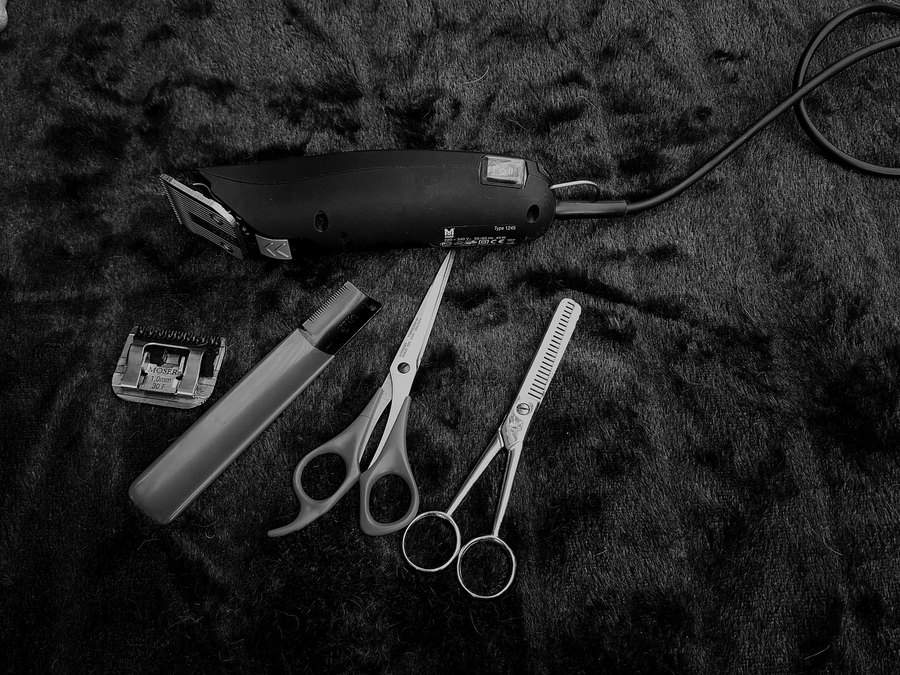 Máquina, tijeras y peines de barbero sobre fondo negro (imagen de referencia)